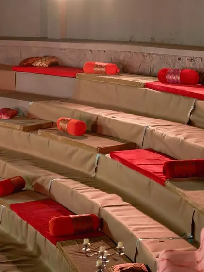 A beautiful 'baithak' style seating arrangement in an amphitheater for an outdoor wedding. The red and gold theme creates a traditional and regal ambiance.
