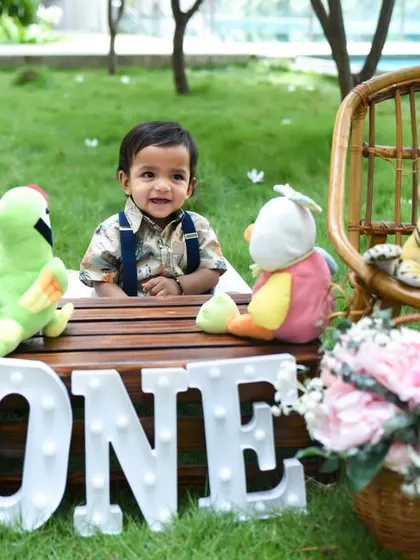 A happy little boy celebrating his first birthday with an outdoor photoshoot. We bring our props to the park to create a beautiful and natural setting.