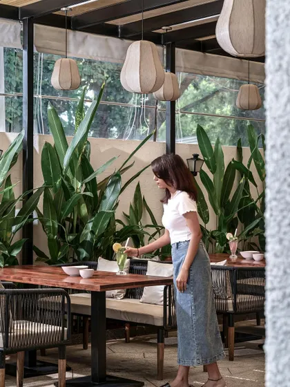 The details matter in creating an experience. Here, the texture of the woven chairs, the warmth of the wooden tables, and the soft glow of the lights contribute to the restaurant's inviting character.