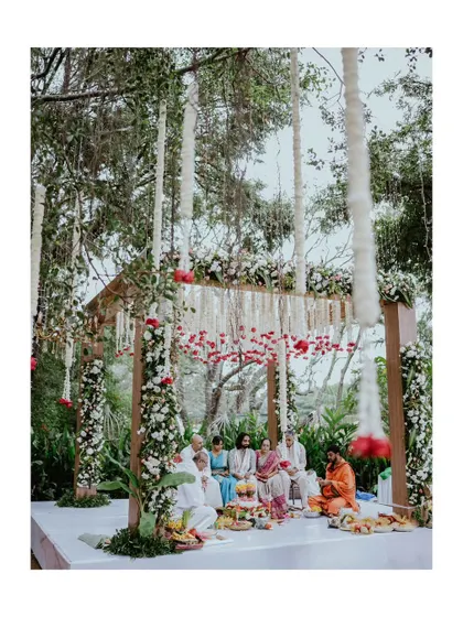 A beautiful wide shot of the wedding mandap, decorated with hanging flowers, where the ceremony is taking place.
