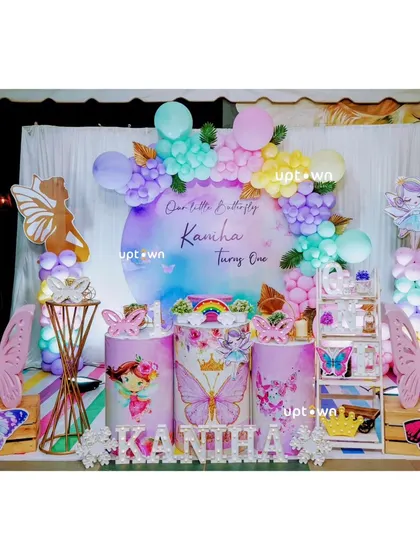 The full setup for Kanha's party, showing the colorful balloon arch and fairy cutouts.