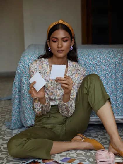 A single model looking through photos, creating a personal and introspective moment. The soft, natural lighting and casual pose make this a charming and effective lifestyle image for the brand.