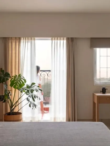 A wide view of the master bedroom, showing the calm color palette, minimalist furniture, and the connection to the outdoor balcony.