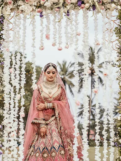 A portrait of a bride standing under a floral archway with hanging tuberose, highlighting our detailed floral work.