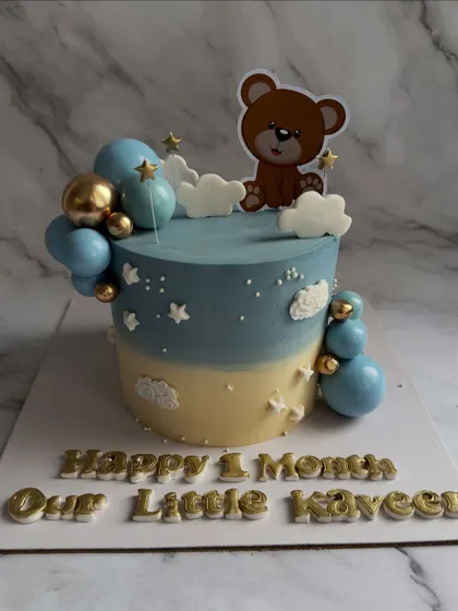 Celebrating one whole month with this adorable teddy bear cake. The blue and gold balloon accents and starry details make it a sweet way to mark a baby's first milestone.