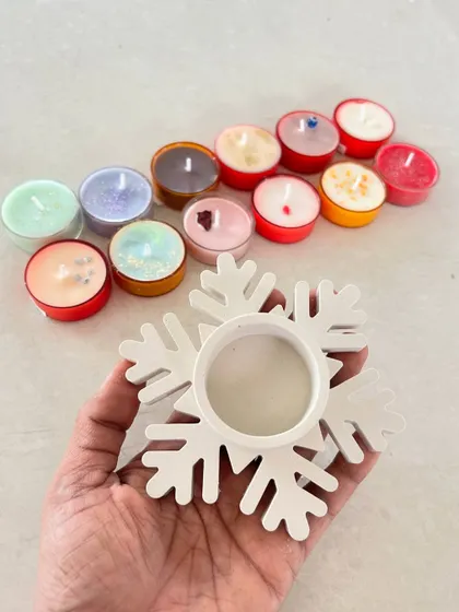 A set of colorful tea light candles with a snowflake-shaped holder, perfect for festive gifting.