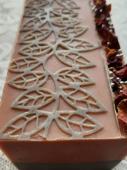 A full, fresh loaf of my Charcoal Rose soap, just poured and decorated. The top is adorned with dried rose petals and a delicate stencil pattern, hinting at the beauty within.