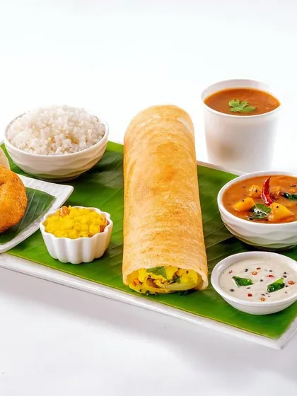 A South Indian platter featuring a masala dosa, idli, vada, and sambar, served on a traditional banana leaf. This vibrant composition captures the essence of a classic South Indian breakfast.