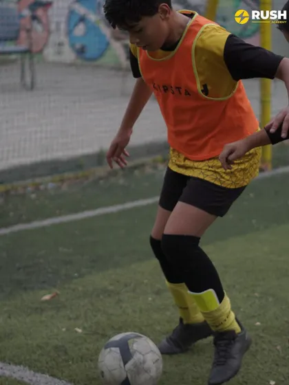A player maintains control of the ball while being challenged by a teammate.