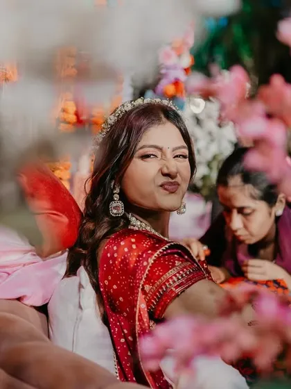 A playful, through-the-flowers shot of the bride making a funny face during her Mehendi ceremony.