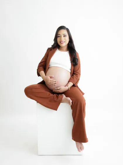 A duplicate of image 301, this confident and happy portrait features a mom-to-be seated in a stylish brown suit.