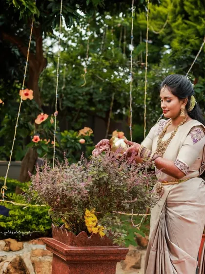 A serene moment in a beautiful garden setting. This client is wearing a lovely off-white saree with a blouse featuring subtle purple floral embroidery on the sleeves.