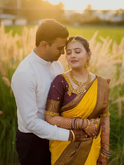 A romantic portrait of a couple in a field at sunset, capturing the golden light and their intimate connection.