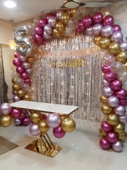 A full view of the elegant pink and gold home decoration for a 5th birthday. The balloon arch and modern cake table create a stylish and celebratory focal point.