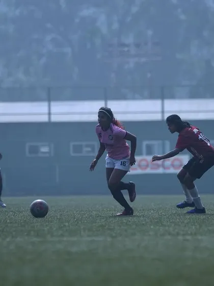 A player dribbling through midfield in foggy conditions, showing focus and determination.