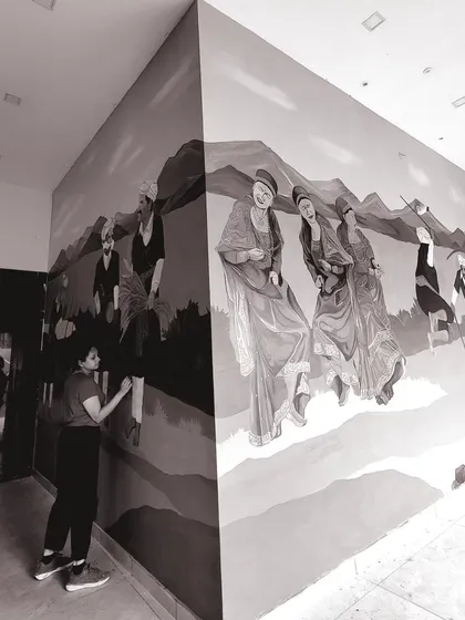 A black and white photo of me working on the large-scale Coorg festival mural.