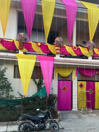 The same house decoration seen during the day, showcasing the vibrant pink and yellow fabric against the building's exterior.