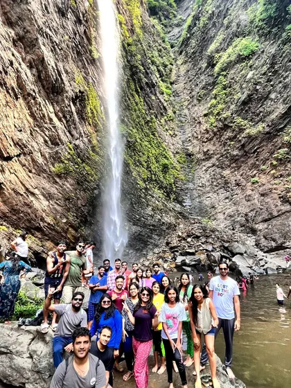 A large group enjoying a waterfall during a long weekend coastal trip.