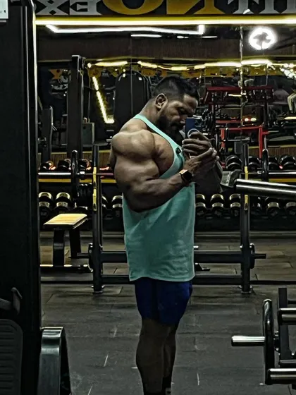 A side bicep pose in a gym mirror.