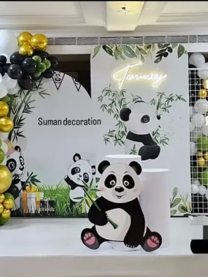 A cute panda theme for a first birthday. This setup includes multiple panda cutouts, a bamboo-themed backdrop, and a balloon arch in green, black, and gold.