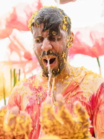 A groom's expressive reaction during a very messy haldi. This shot, set against a whimsical floral backdrop, is full of raw energy and emotion.
