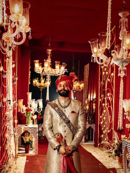 The groom, dressed in royal attire, standing in the beautifully decorated wedding aisle, ready to welcome his bride.