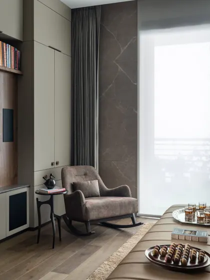A quiet corner in the family lounge, featuring a comfortable rocking chair next to the window. This space is designed for moments of pause, perfect for enjoying a cup of tea and looking out at the view.