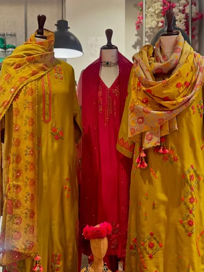 A festive trio in mustard yellow and deep pink. The printed floral dupattas with tassel details add a playful and vibrant touch to these elegant suits.