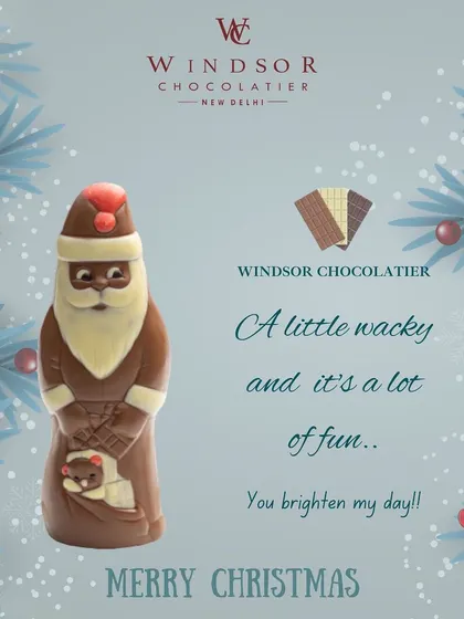 This tall, elegant Santa Claus figurine is crafted from rich milk chocolate with a white chocolate beard, holding a small teddy bear.