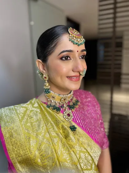 A smiling portrait of Archi. Her traditional jewelry, including the nath and maang tikka, are key elements of her stunning look.