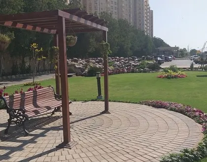 This public park seating area shows how we combine function and beauty. We installed a durable paved circle with a comfortable bench under a wooden pergola, surrounded by a well-maintained lawn and colorful flowerbeds. It’s a perfect example of creating a small, peaceful retreat within a larger green space.