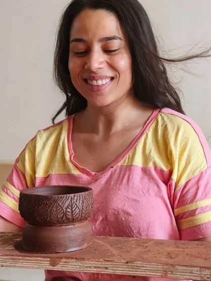 A participant smiles, delighted with the leaf-textured bowl she has just created. Our workshops focus on both wheel throwing and hand-building decoration techniques like texturing.