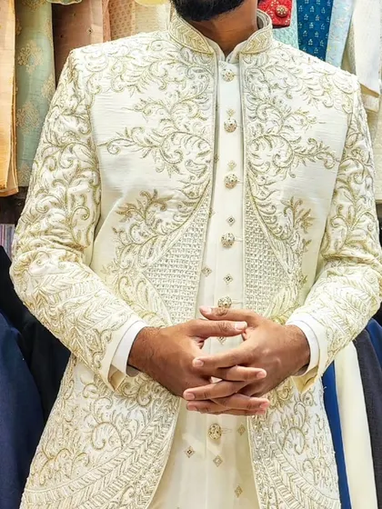 A close-up of a client's hand-embroidered open sherwani in off-white, showing the intricate gold threadwork and the perfect fit.