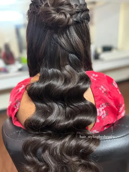 This half-up style combines a braided crown, a small bun, and perfectly sculpted Hollywood waves. It's a very glamorous and polished look, ideal for a formal evening event.
