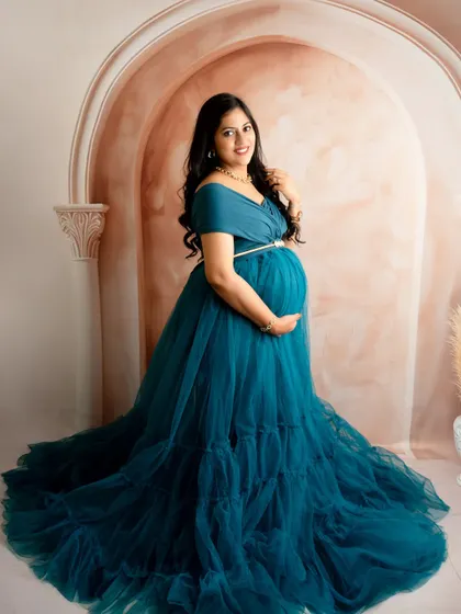 A classic portrait in a teal gown, showcasing its rich color and texture against a simple, elegant archway backdrop.