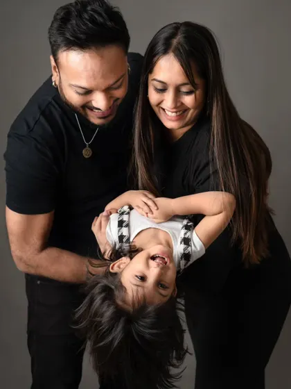 A playful moment with parents swinging their daughter upside down, capturing her delightful laughter.