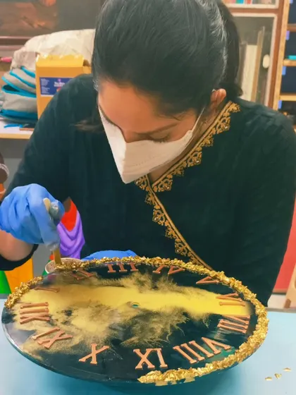 A student carefully adding gold leaf details to her resin clock. We teach various finishing techniques to give your artwork a professional and polished look.
