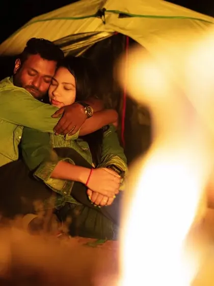 An embrace filled with warmth and affection, seen through the dancing flames of the bonfire. The fire creates a soft, romantic glow, making the moment feel even more intimate.