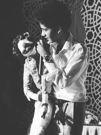 A dramatic black and white photo of me performing with one of my classic ventriloquist dolls. I use a variety of puppets to create different characters and comedic situations in my shows.