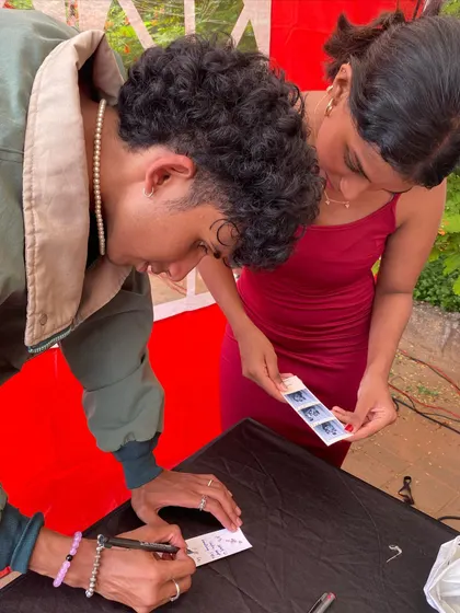 A candid moment of friends personalizing their photo strip keepsakes.