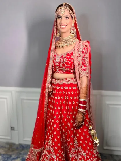 This bride looks radiant and happy in her classic red lehenga. The makeup is bright and fresh, perfect for a day wedding.
