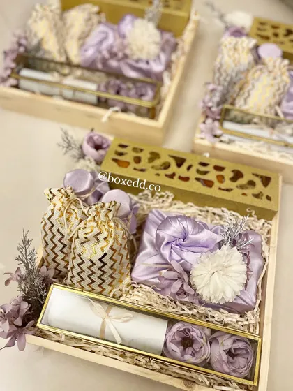 A detailed shot of our lavender-themed wedding invitation hamper. You can see the intricate details, from the scroll invitation to the satin-wrapped gifts and delicate floral arrangements.