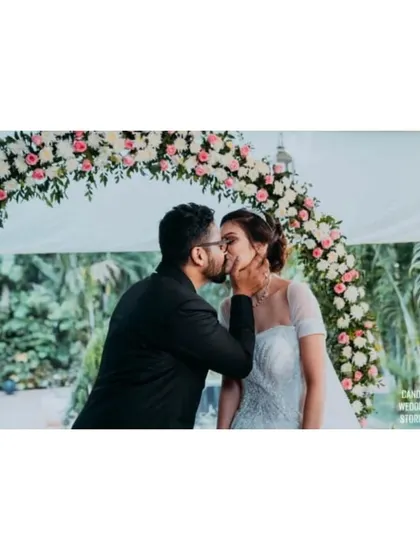 A romantic kiss under a floral arch, a perfect portrait moment during their outdoor reception.