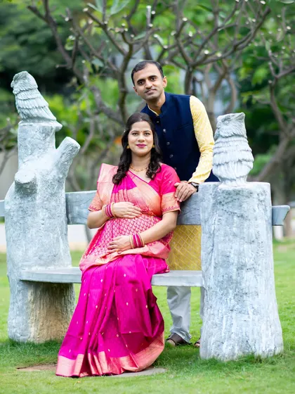 A seated portrait of a couple in traditional attire, using a unique park bench as a prop. This showcases how we incorporate the environment into your photos.