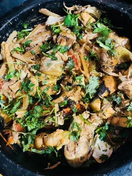 A beautiful dish of fish cooked with bamboo shoot, banana flower, and banana stem, garnished with fresh coriander.