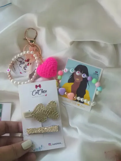 The contents of our gold-themed love hamper, including a "LOVE" bracelet, a heart keyring, and a set of two gold-tone hair clips.