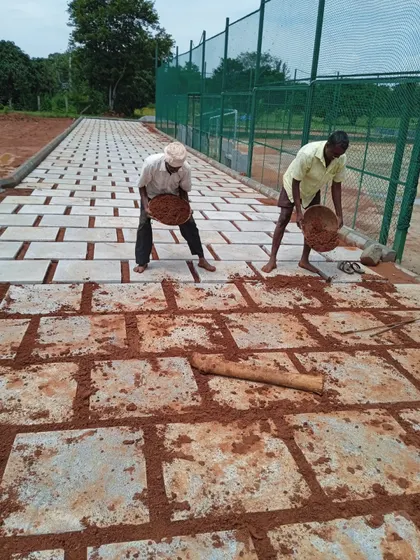 My team at work, laying down red soil between freshly laid stone pavers on a new pathway. This shows the manual process and attention to detail during installation.