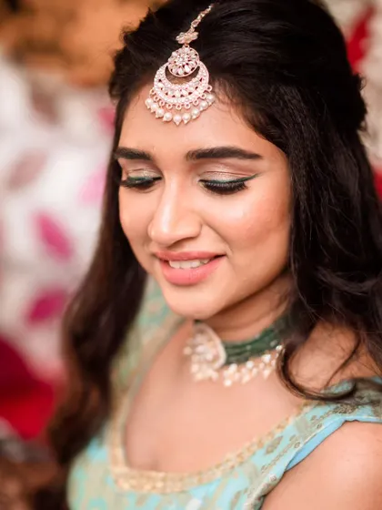 Fun and candid moments from a mehendi ceremony. The bride's makeup is fresh and playful, with a winged liner and glowing skin, perfect for celebrating with her loved ones. The hairstyle is a soft half-updo with pretty accessories.