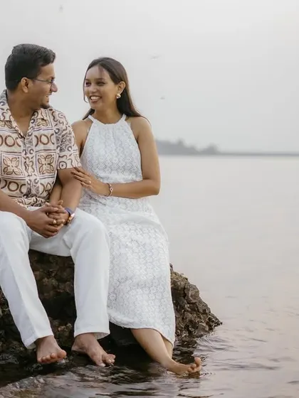 A quiet, shared moment as the couple sits on a rock by the lake, their feet touching the water.