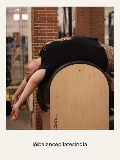 That post-stretch feeling! A client enjoys a deep backbend over the Pilates barrel, a piece of equipment we use for spinal mobility and core work.